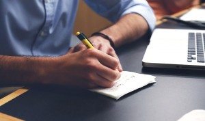 person writing and researching on a notepad 