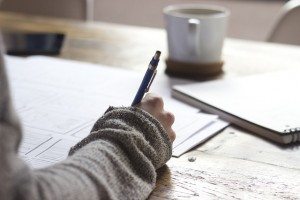 person using pen to write on paper