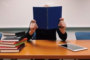 person reading book in a classroom with ipad on the table