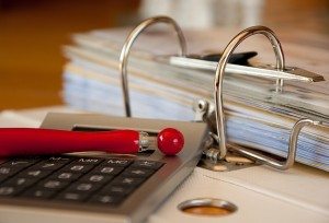 a calculator and pen sitting on top of a binder of paperwork