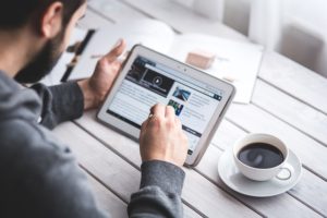 a man reading an article on his tablet and using a stylus to click links