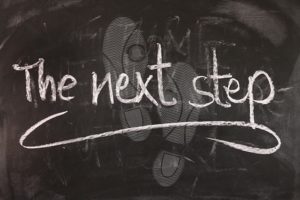 A chalkboard with footsteps and the words the next step.