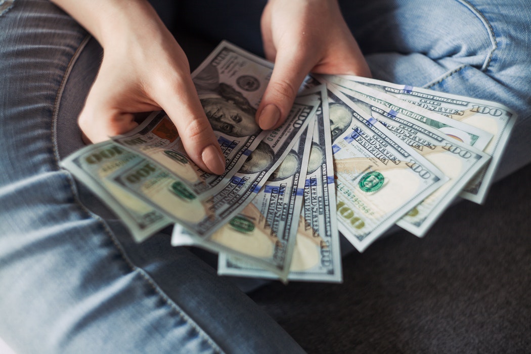 A person holding several one hundred dollar bills.